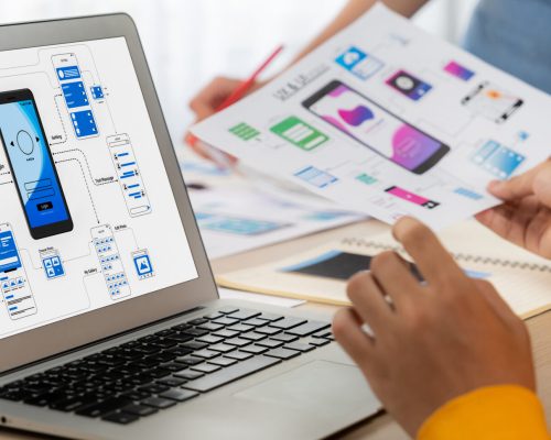 Panorama banner of startup company employee planning on user interface. Synergic Panorama banner of startup UX developer or company employee design user interface or UI prototype for mobile application or website software with software display on laptop monitor in office. Synergic